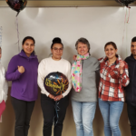 2023-24 English Class. One man and five women standing in front of white board with balloons.